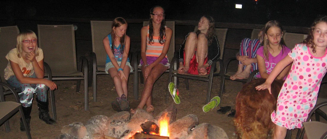 Girls hanging around a fire at Horse Camp