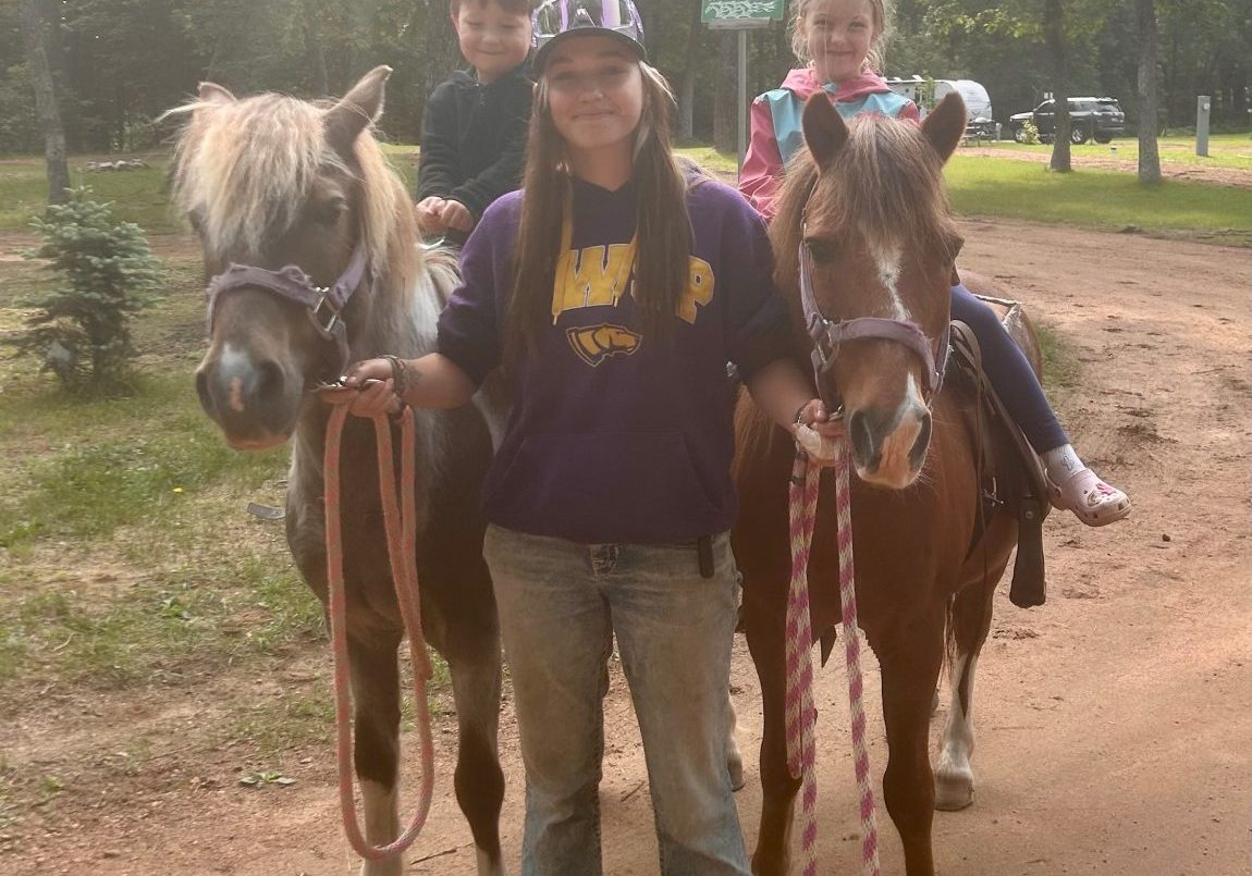Rylie guiding two small children on a pony ride.